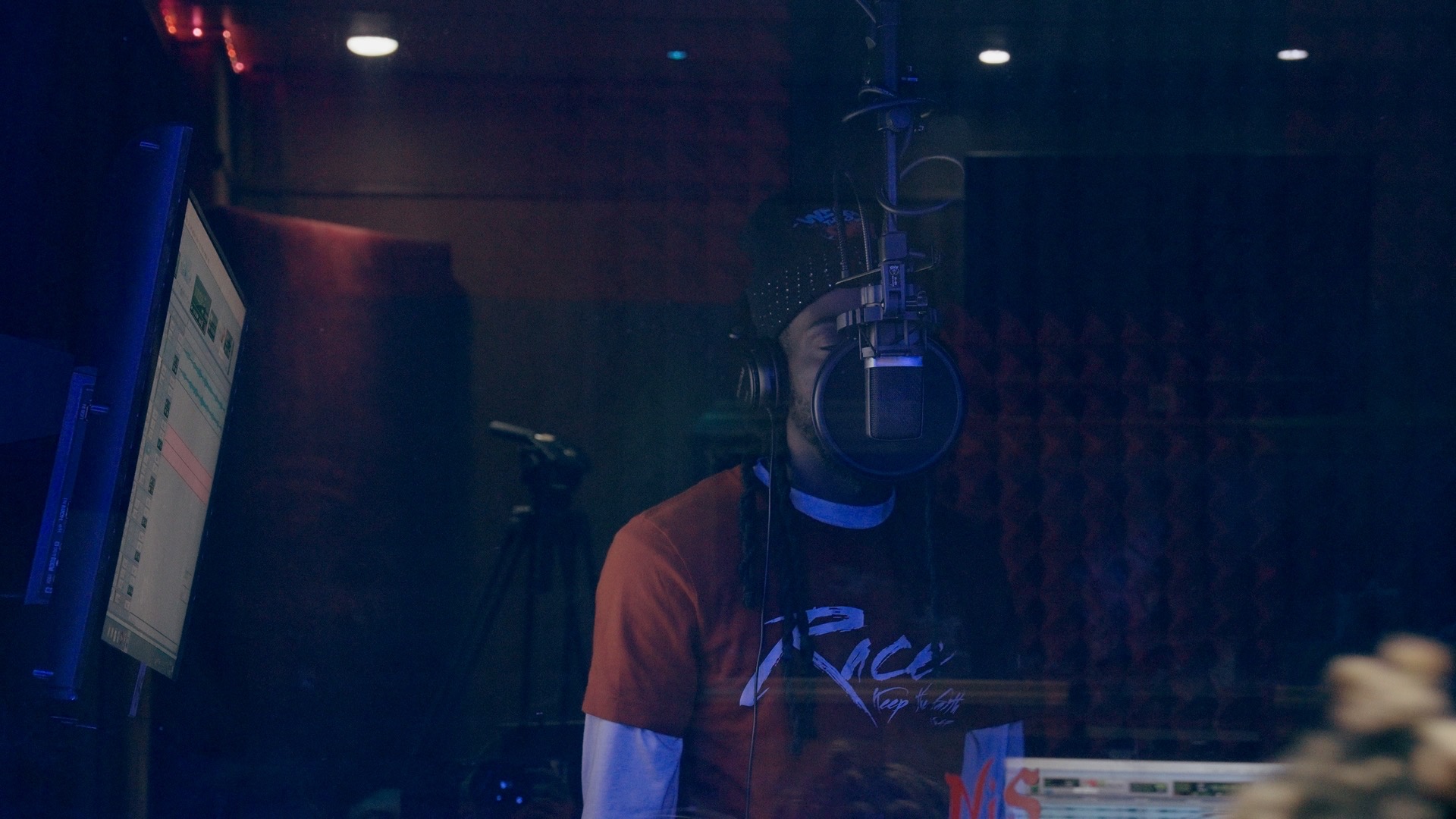 Artist recording vocals through the studio booth glass